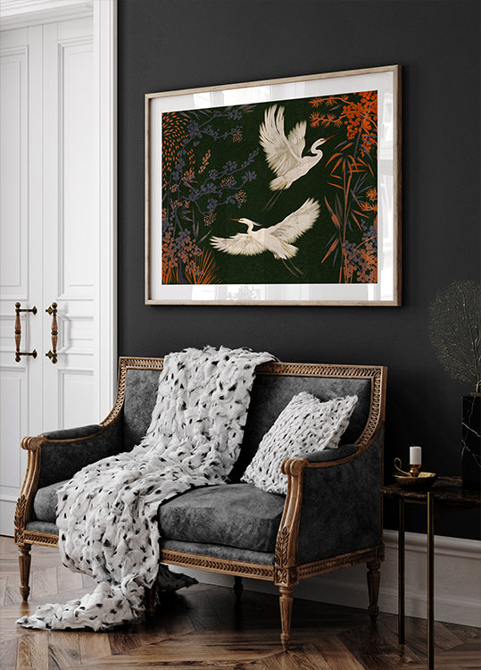 un canapé noir et blanc avec une couverture blanche et deux oreillers blancs, posé contre un mur sombre avec une peinture encadrée de deux oiseaux blancs en vol au-dessus.