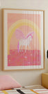 une affiche encadrée d'une licorne avec une palette de couleurs rose et blanche, sur un fond rose et jaune avec une arche arc-en-ciel.