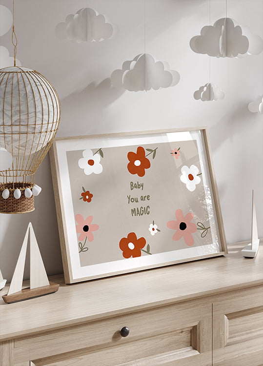 Une impression encadrée avec un motif floral et le texte « Baby You are Magic » est exposée sur une commode en bois, avec une lanterne décorative en papier suspendue au-dessus.